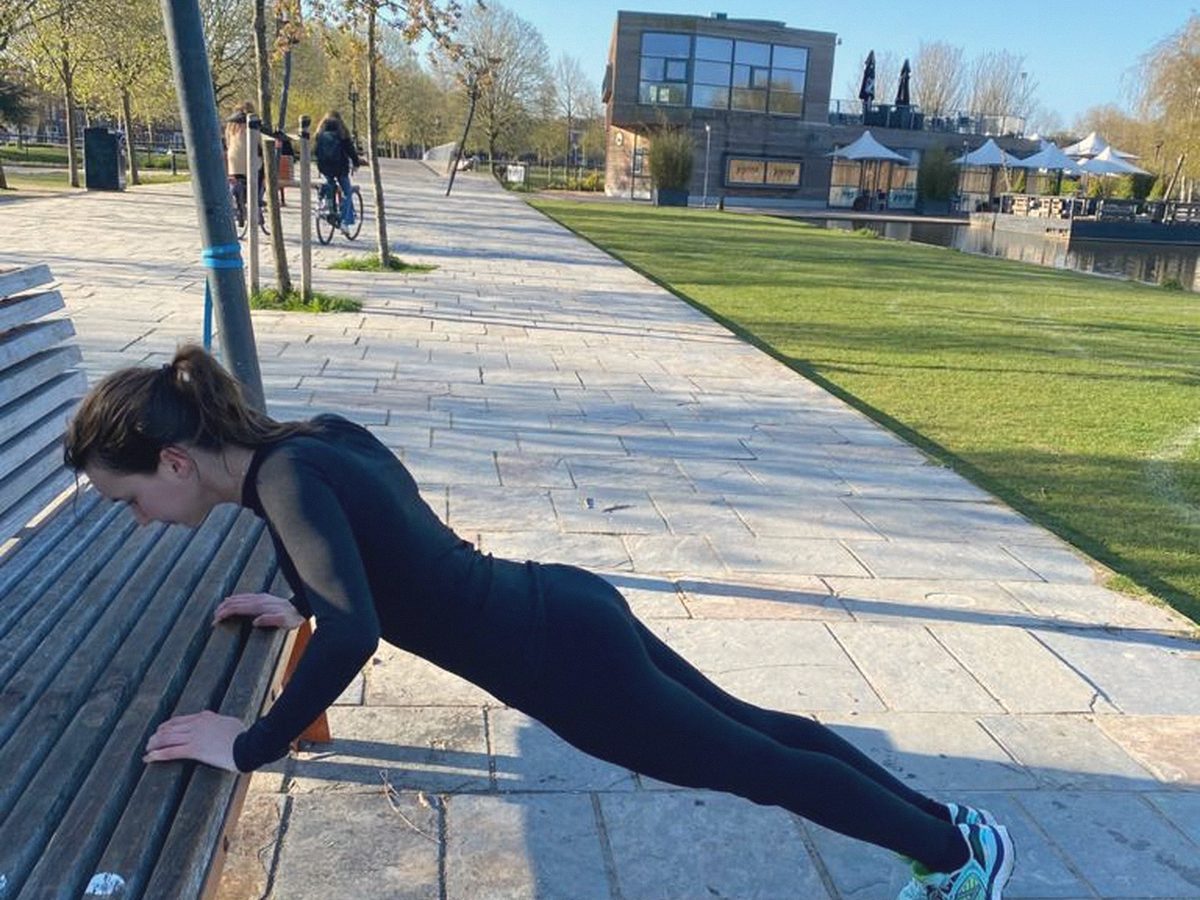 Iemand doet een oefening op een bankje in een park