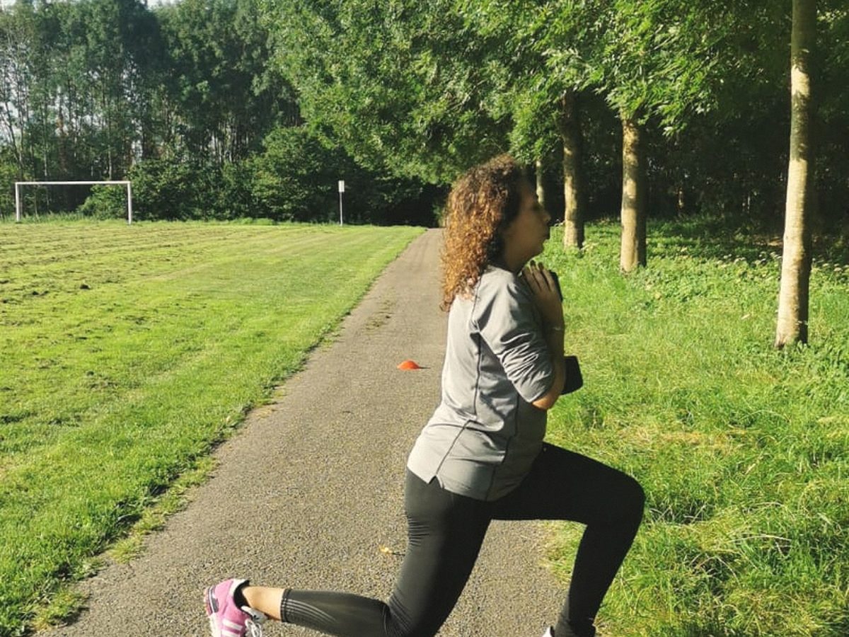 Iemand doet een uitvalspas op een grasstrook langs een pad